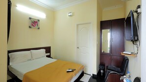 Een hotelkamer met een bed, bureau, stoel, televisie en kledingkast.