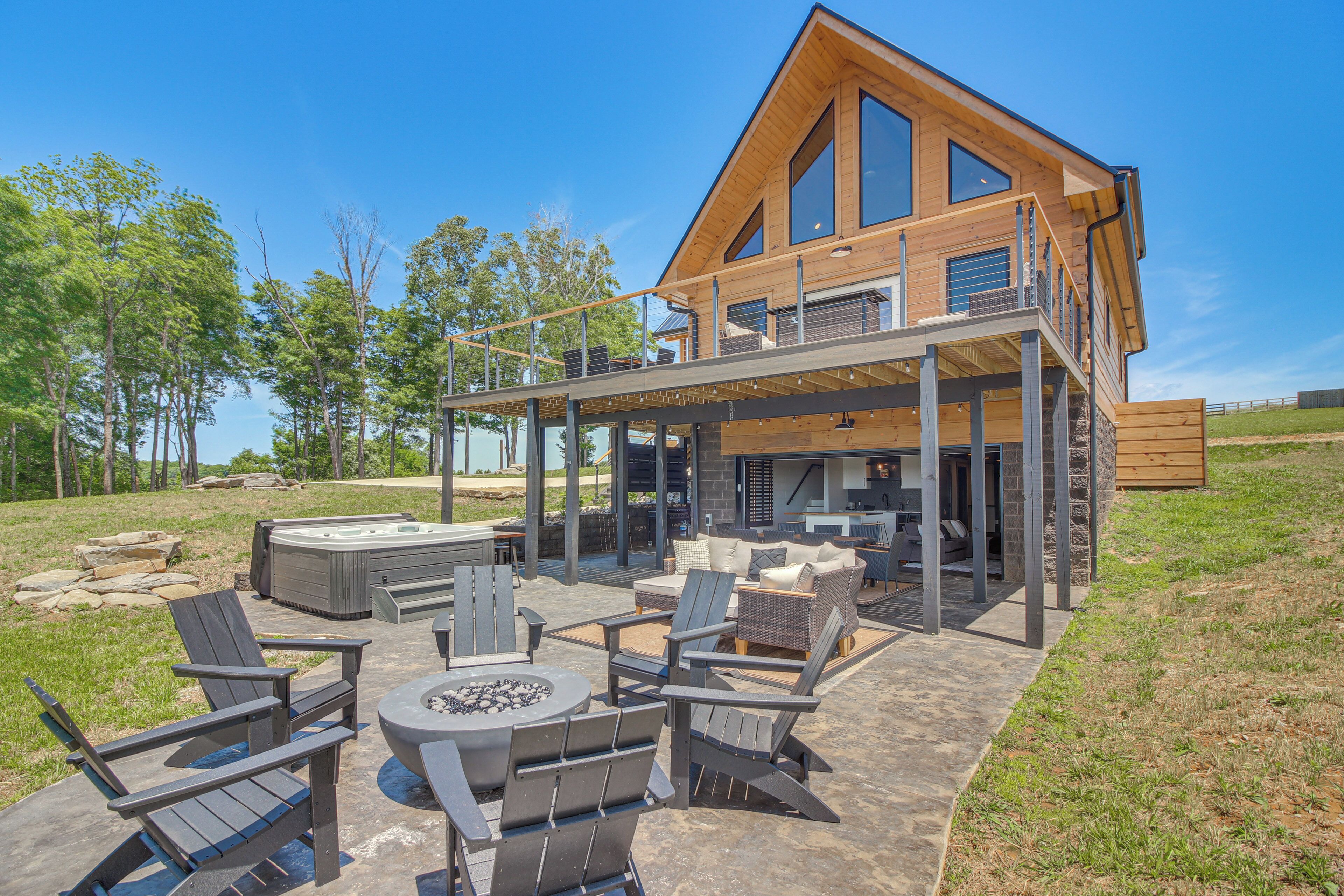 A modern house with a covered patio area featuring outdoor furniture and a fire pit.