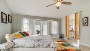 Een slaapkamer met een bed, nachtkastje, lamp en een kleurrijk vloerkleed.