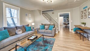 Ein modernes Wohnzimmer mit einem grauen Sofa, einem Couchtisch und einer Treppe, die in einen Essbereich führt.