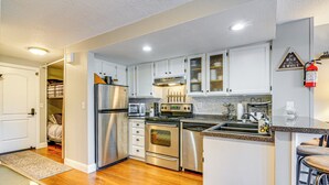 A modern kitchen with stainless steel appliances, white cabinets, and a wooden floor. - Romantic Ski Haven w/ Balcony: Brian Head Studio (Brian Head)