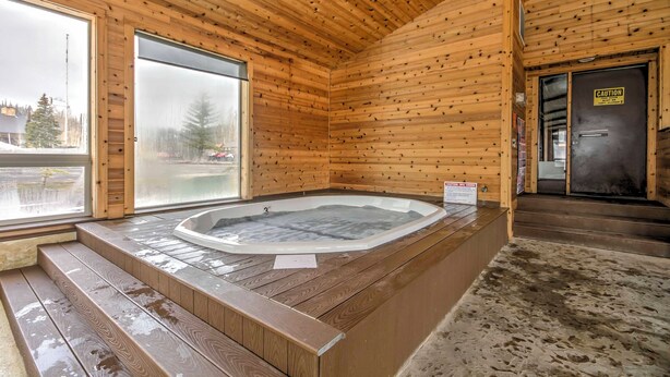 A wooden cabin with a hot tub, wooden steps, and a large window. - Romantic Ski Haven w/ Balcony: Brian Head Studio (Brian Head)
