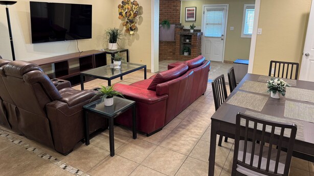 A living room with a leather sofa, a glass coffee table, a TV, and a fireplace. - 4 bedrm, 8 Guest house in Central Phoenix WiFi, Putting Green, Mountain Preserve (Phoenix)