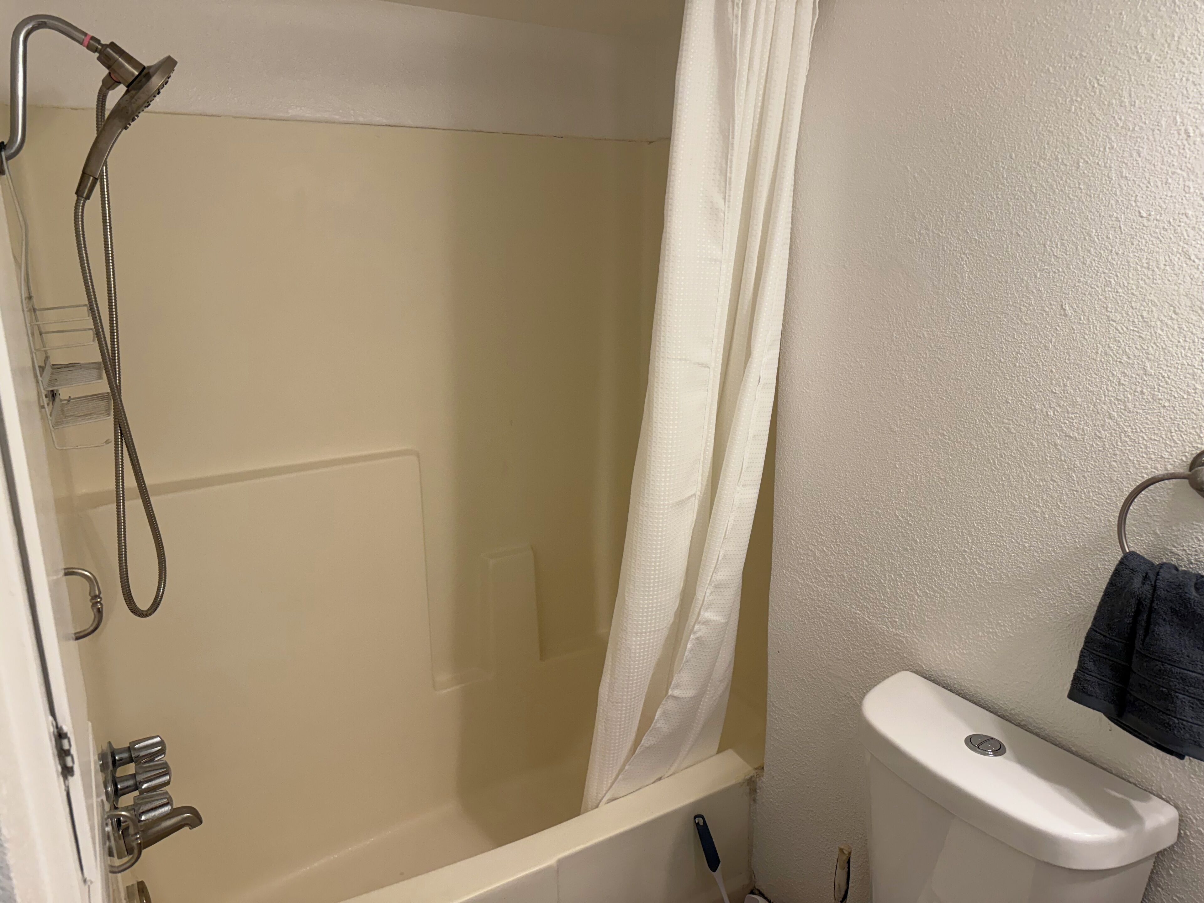 Une salle de bain avec une douche, des toilettes et une serviette accrochée au mur.