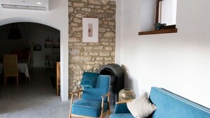 A cozy living room with a stone wall, a fireplace, a blue sofa, and a blue armchair.