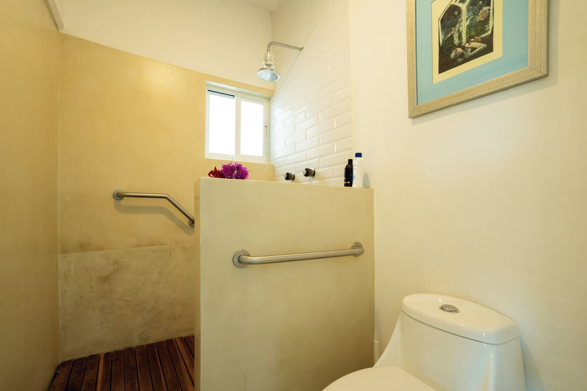 Ein Badezimmer mit Dusche, Toilette und Fenster.
