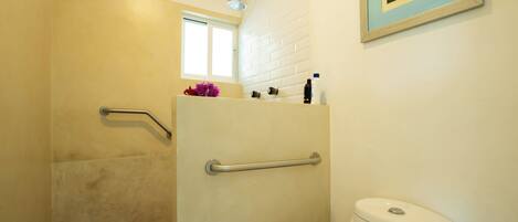 Ein Badezimmer mit Dusche, Toilette und Fenster.