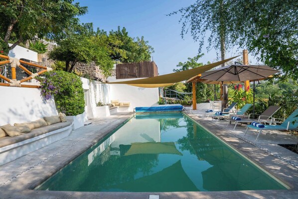 A swimming pool with lounge chairs and a canopy.