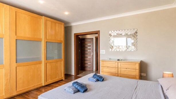 Ein Schlafzimmer mit einem Bett, einem Holzschrank, einem Schminktisch und einem Spiegel.