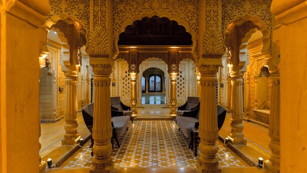 An ornate hallway with intricate arches and columns, leading to a pool area. - Hotel Durjay Garh (Jaisalmer)