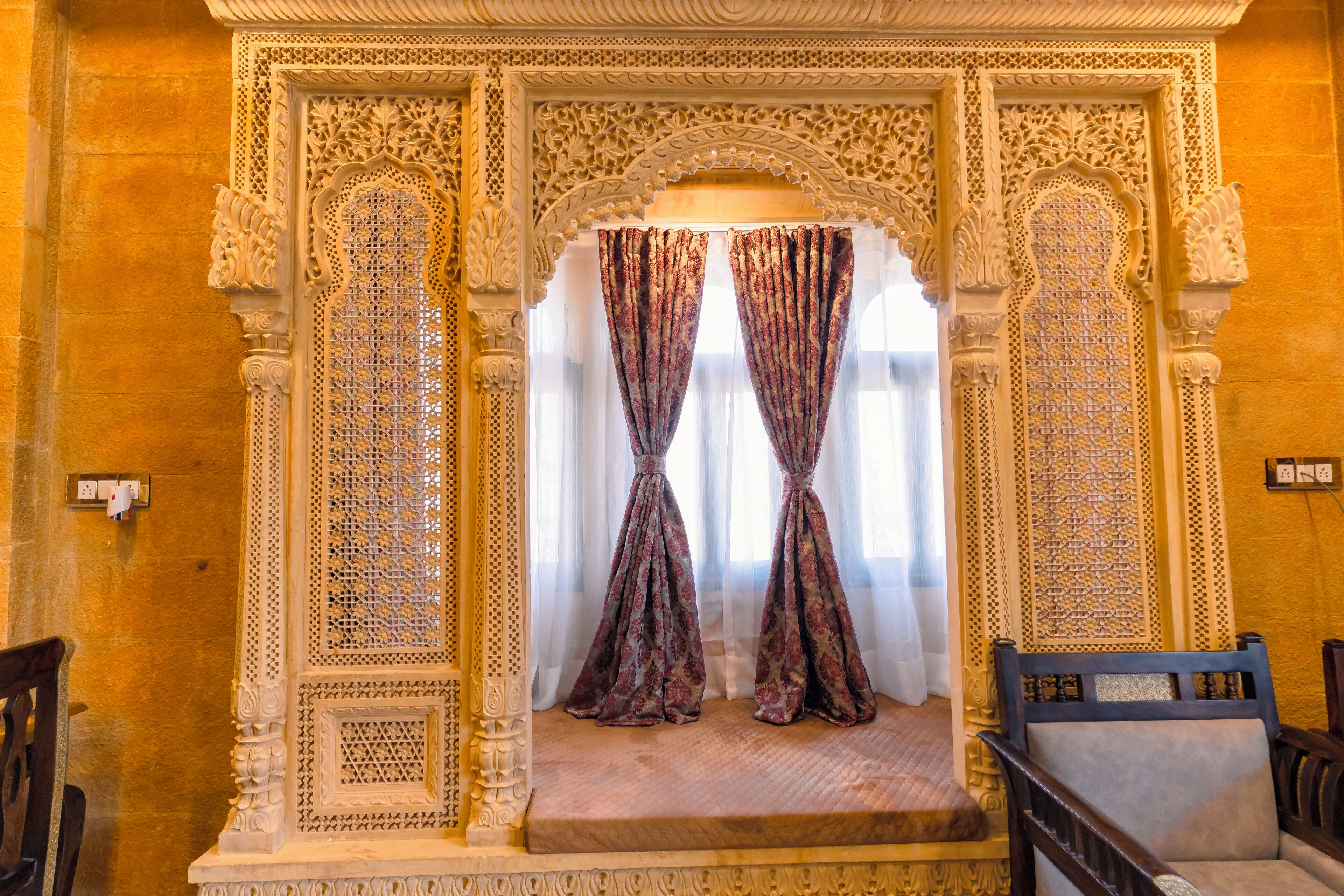 Une alcôve richement décorée de sculptures, avec un banc et des rideaux.