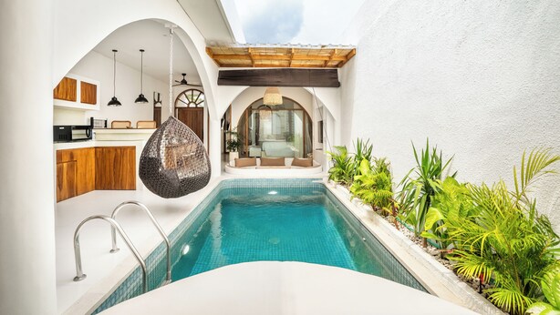A modern pool area with a clear view of the pool, a wooden ceiling, and a seating area with cushions.