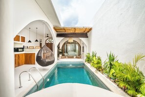A modern pool area with a clear view of the pool, a wooden ceiling, and a seating area with cushions. - La Feliz Villa Seminyak (Denpasar)