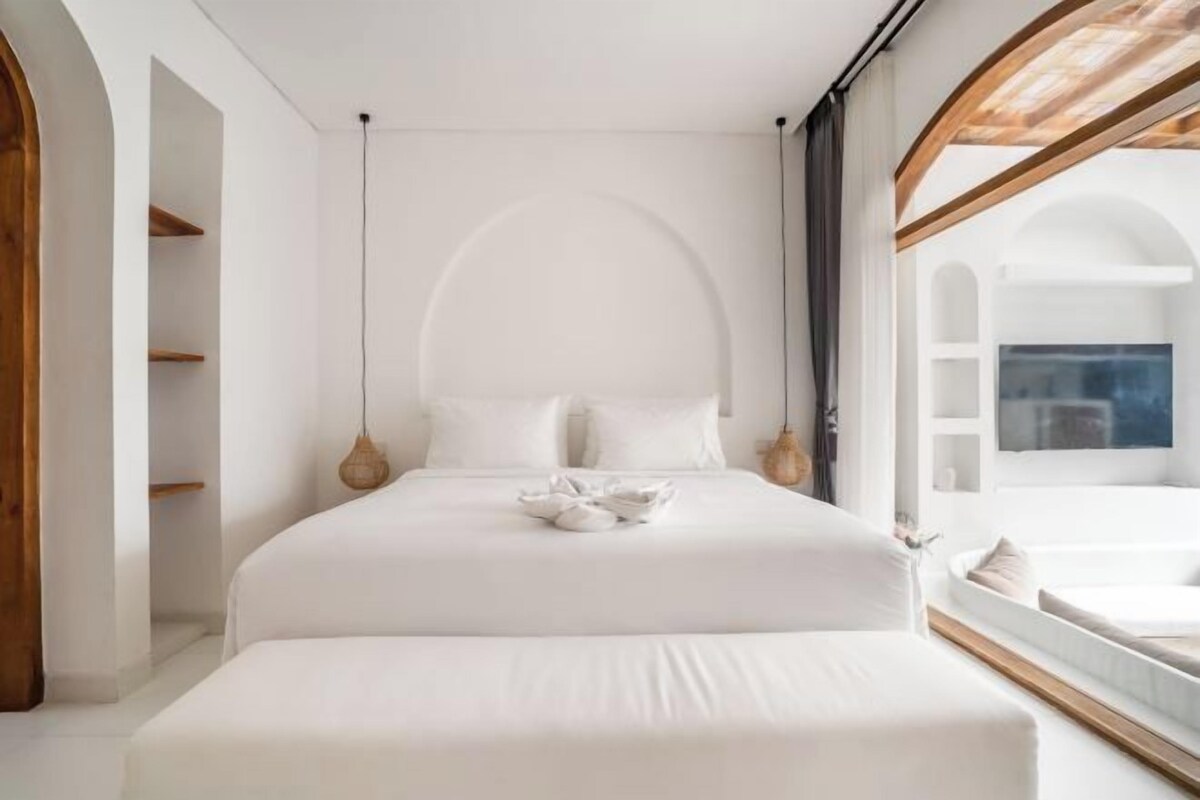 Un dormitorio moderno con una cama grande, vigas de madera y vistas al exterior.
