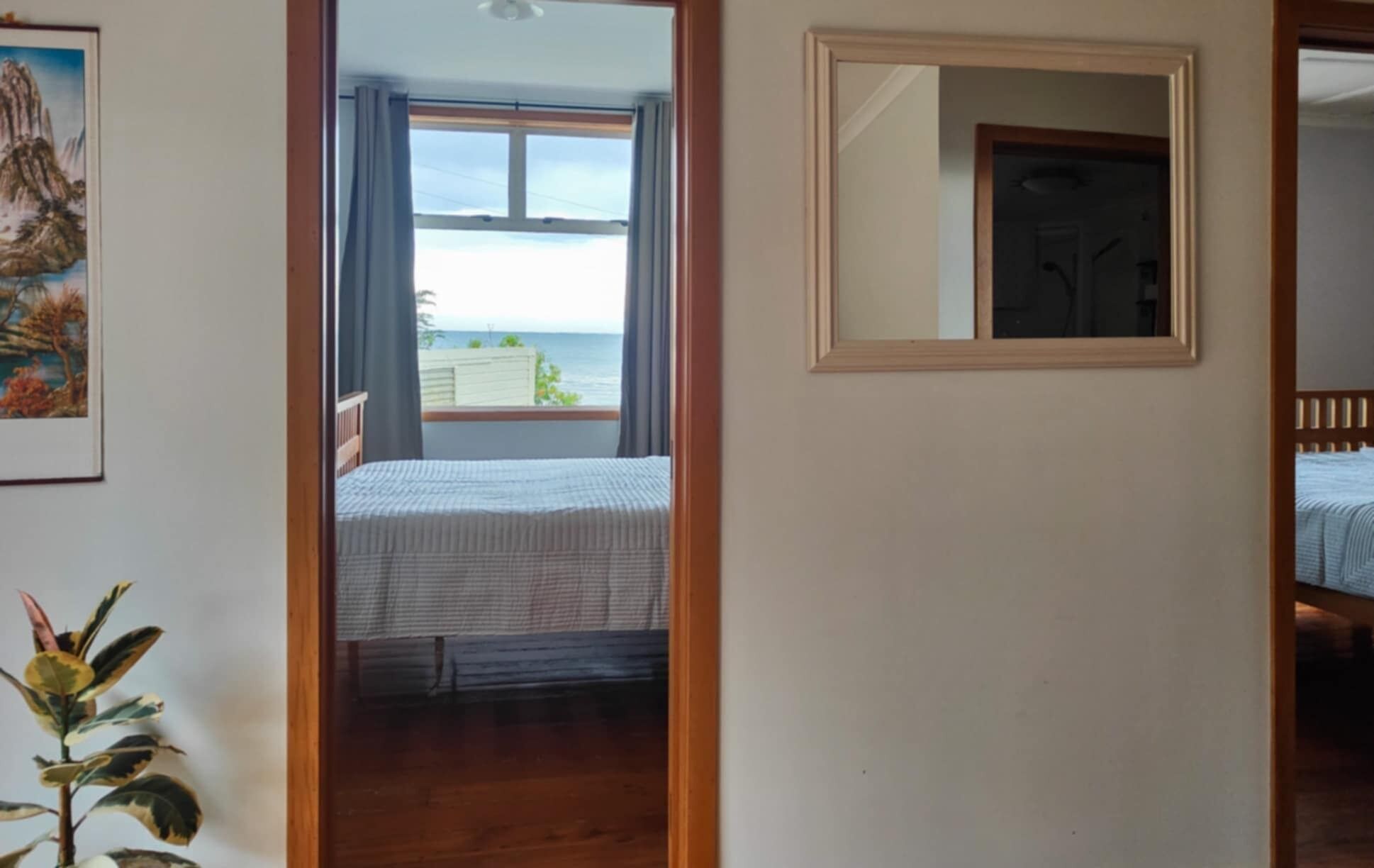 Une chambre à coucher avec un lit, une fenêtre avec des rideaux et une vue sur la mer.