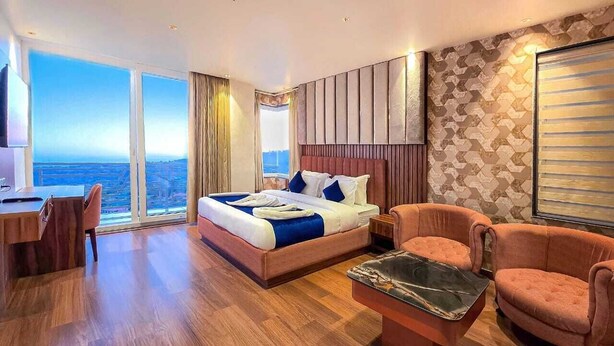 Una habitación de hotel con una cama grande, un escritorio, una silla y vistas a la ciudad.