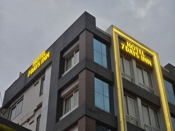 Un hôtel au design moderne, reconnaissable à son grand panneau indiquant « HOTEL 7 DAYS INN ».