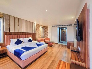 Une chambre d’hôtel moderne dotée d’un grand lit, d’une télévision, d’un coin salon et d’un plancher en bois.