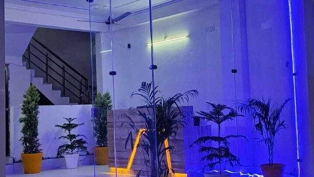 Entrada del hotel Gange Hill con puertas de cristal, plantas en macetas y una escalera que sube.