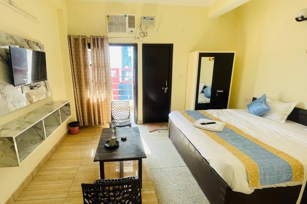 A hotel room with a bed, a TV mounted on the wall, a small table, and a chair.