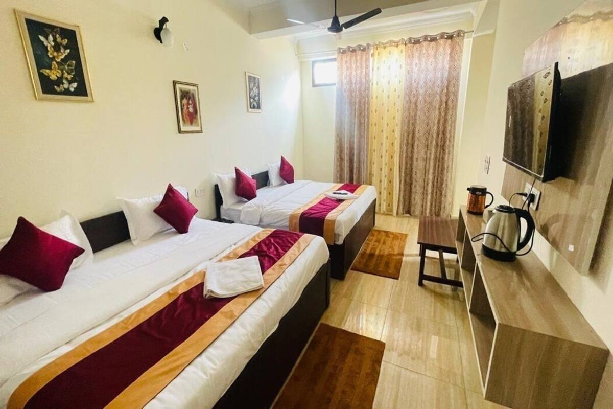 A hotel room with two beds, a TV, a coffee maker, and a small table.