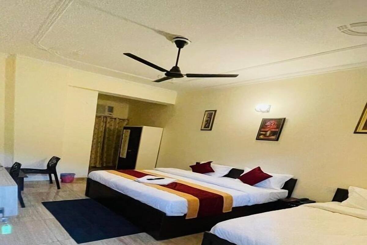 A hotel room with two beds, a desk, and a ceiling fan.