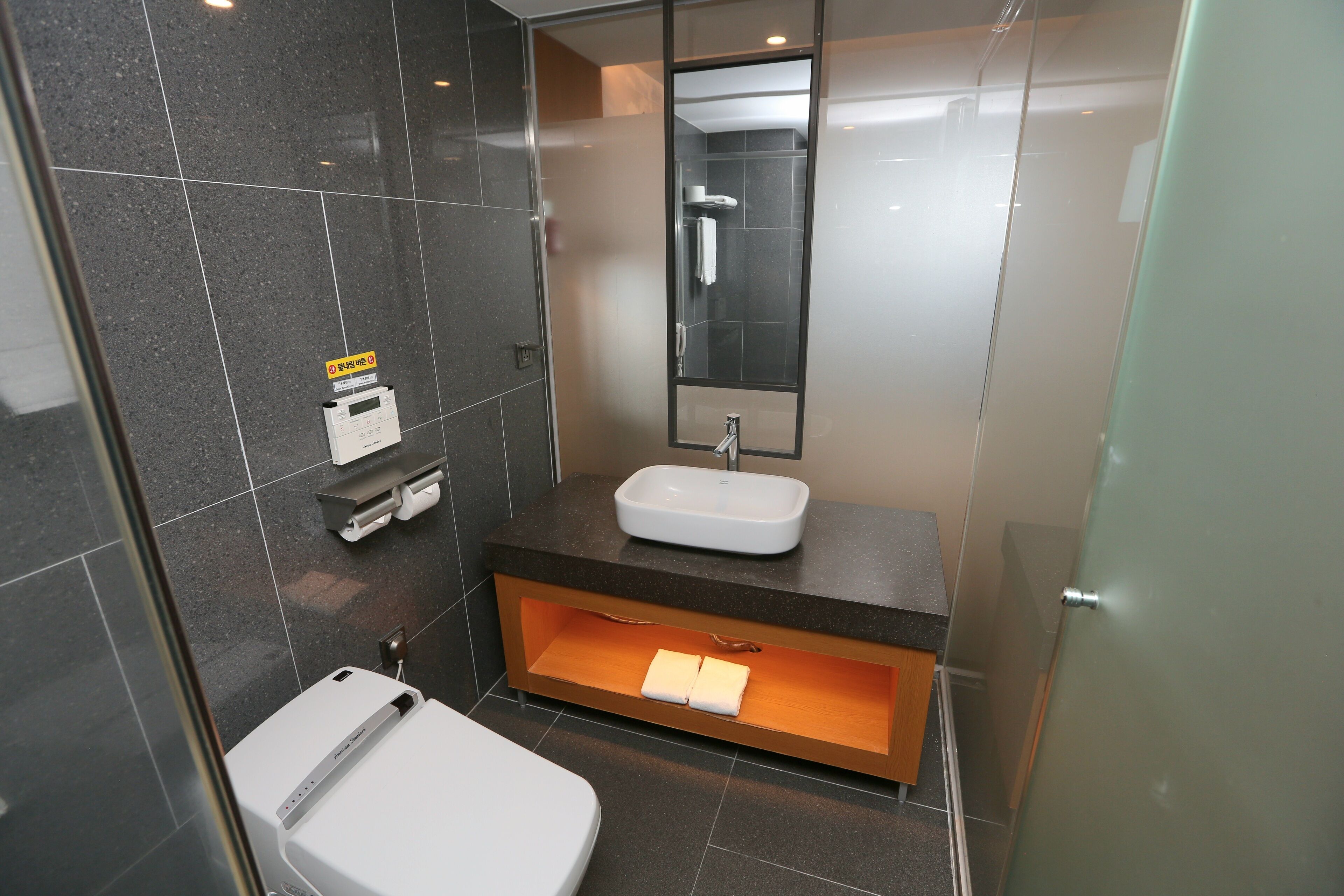 Une salle de bain moderne avec un lavabo blanc, une douche en verre et un meuble-lavabo en bois.