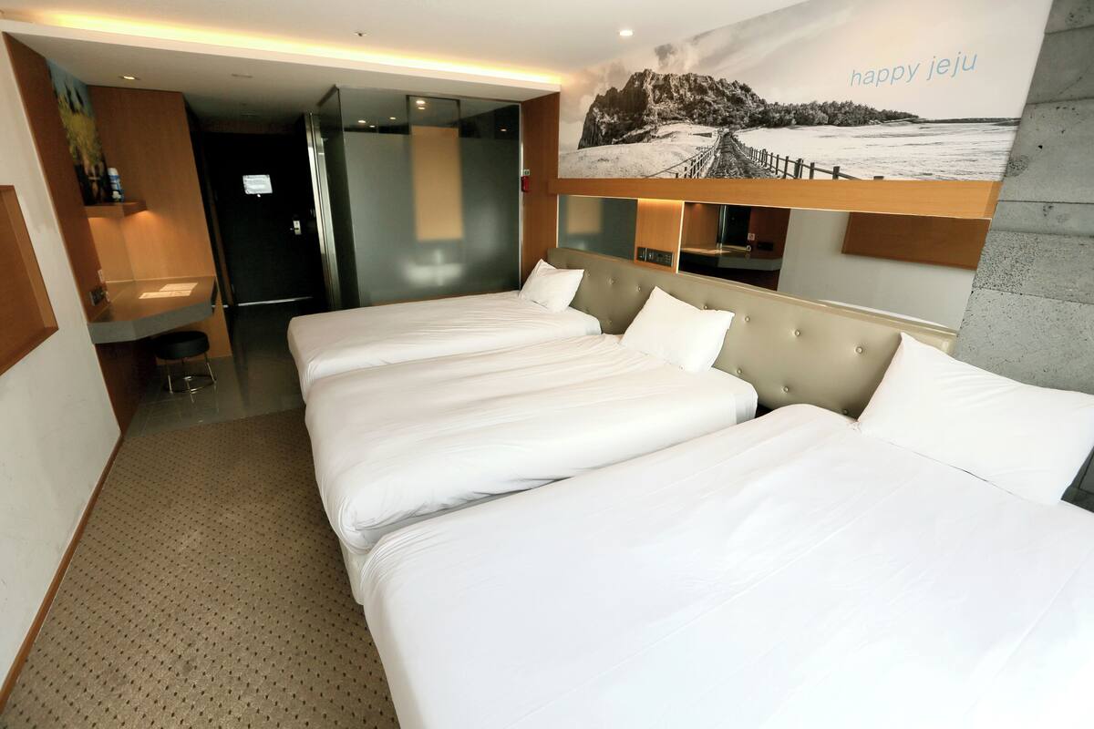 Een hotelkamer met twee bedden, een badkamer en een groot raam met uitzicht op een besneeuwd landschap.