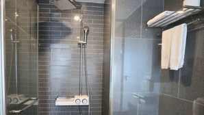 A modern shower area with a handheld showerhead, a wall-mounted faucet, and a control panel.