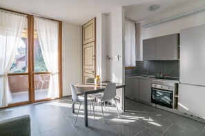 A modern kitchen with a dining area, a sliding glass door to a balcony, and a small oven. - GuestHost - Cosy and bright apartment of 65 sqm, located on the first floor of a building (without lift) with a shared garden and private parking space.The property is located in the lakeside village of Pusiano and enjoys a splendid lake view, which can  (Pusiano)