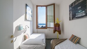Un dormitori amb dos llits, una finestra amb vistes, una perxa i una porta amb clau.