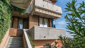 Edifici de dues plantes amb un balcó, una escala i una porta amb finestral.