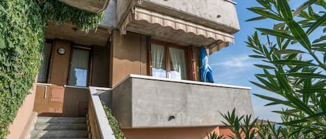 A two-story building with a balcony, a staircase, and a door with a window.