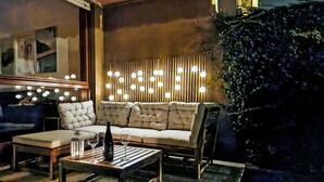 A modern outdoor seating area with a sofa and a coffee table, a decorative light fixture, and a stone wall. - Nice apartment for 3 guests with WIFI, A/C, TV, patio and pets allowed (Lesa)