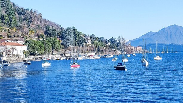 A coastal marina with boats docked, buildings along the shore, and a mountain in the background. - Nice apartment for 3 guests with WIFI, A/C, TV, patio and pets allowed (Lesa)