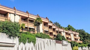 A multi-story hotel with balconies and a view of the surrounding greenery. - Nice apartment for 3 guests with WIFI, A/C, TV, patio and pets allowed (Lesa)