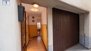 A hallway with a wooden floor, a brown door, and a number 1 sign on the wall.