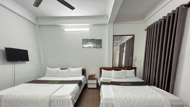 A hotel room with two single beds, a flat-screen TV, a ceiling fan, and a large window with curtains. - Huong Villa Hotel HN - by BAY LUXURY (Hanoi)