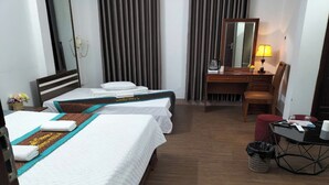 A hotel room with two beds, a desk, a chair, a lamp, and a waste basket. - Huong Villa Hotel HN - by BAY LUXURY (Hanoi)