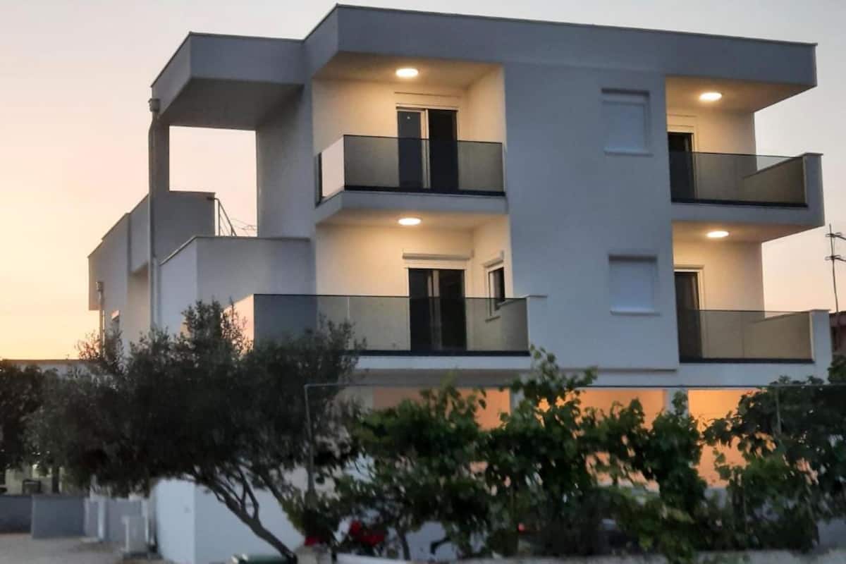 A modern multi-story building with balconies and a flat roof.