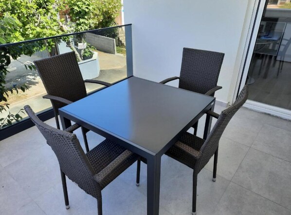 Un balcon avec une table et quatre chaises.