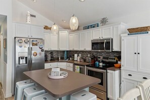 A modern kitchen with white cabinetry, stainless steel appliances, and pendant lighting.