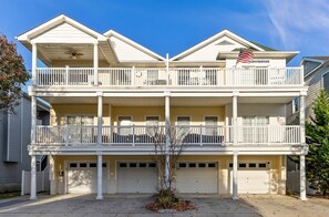 A two-story residential building with a balcony on each floor, a garage, and an American flag.