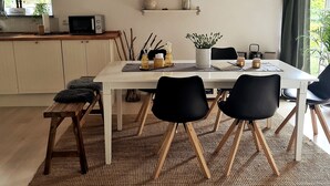 A modern kitchen with a white countertop, a microwave, and a dining area with a white table, black chairs, and a bench. - Apartment 'Nordsee- Ferienwohnung Im Speicher' with Wi-Fi (Meldorf)