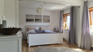 A bedroom with a bed, a radiator, a window with curtains, and wall art. - Apartment 'Nordsee- Ferienwohnung Im Speicher' with Wi-Fi (Meldorf)