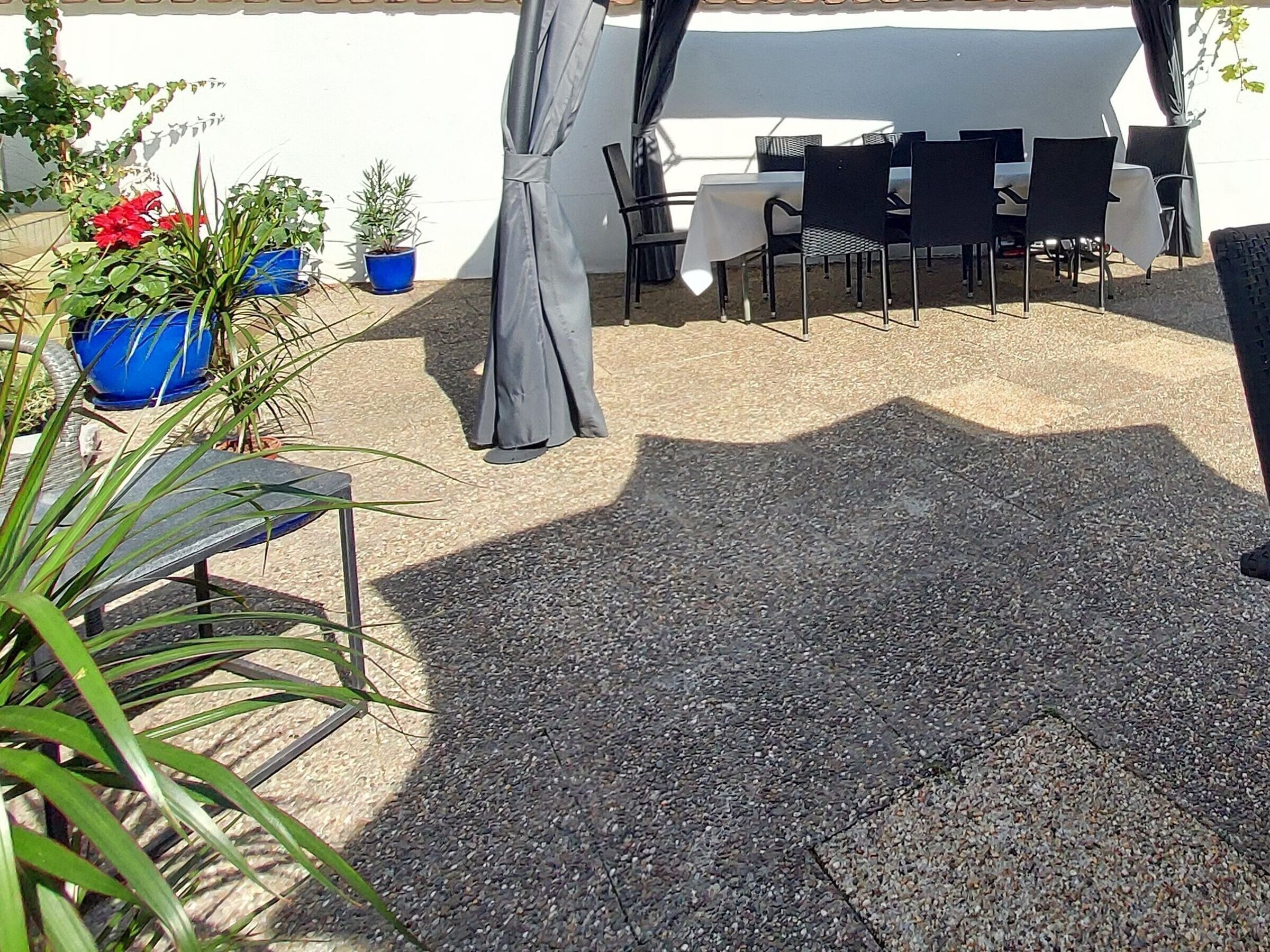 Un'area patio all'aperto con tavoli e sedie, piante in vaso e una zona relax coperta.