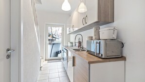 A modern kitchen with a built-in microwave, a sink, and a wooden countertop. - Apartment 'Schlosspark 1' with Wi-Fi (Worms)