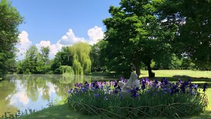 A serene park with a pond, lush greenery, and a statue surrounded by purple flowers. - Apartment 'Schlosspark 1' with Wi-Fi (Worms)