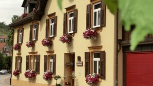 Un bâtiment doté de nombreuses fenêtres, dont certaines sont pourvues de volets, et orné de jardinières sur sa façade.