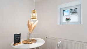Una mesa de comedor blanca con un candelabro, un cartel y una ventana con persianas.